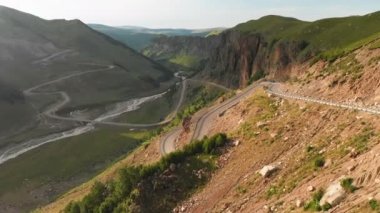 Derin bir geçitte bir dağ asfalt yol serpantin ile bir manzara üzerinde yakın çekim uçan havadan görünümü. Uzak dağlık alanlarda ulaşım iletişimi kavramı