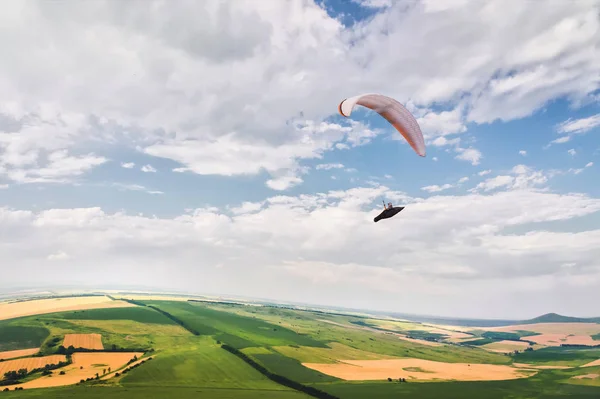 A paraglider flies in the sky in a cocoon suit on a paraglider over the Caucasian countryside with hills and mountains. Paragliding Sport Concept — Stock Photo, Image