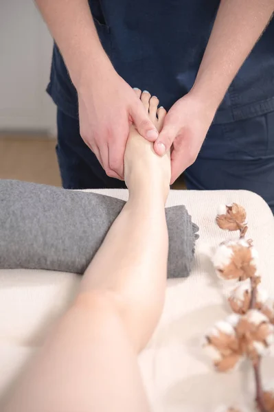 Blízkému lázeňském salonku mužského fyzioterapeutka dělá masáž nohou mladé dívce. Koncepce pro zdraví nohou a profesionální masáž — Stock fotografie
