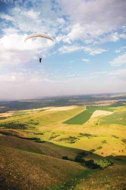 Bir yamaç paraşütü tepeler ve dağlar ile Kafkas kırsal üzerinde bir yamaç paraşütü üzerinde bir koza takım elbise gökyüzünde uçar. Yamaç Paraşütü Spor Konsepti