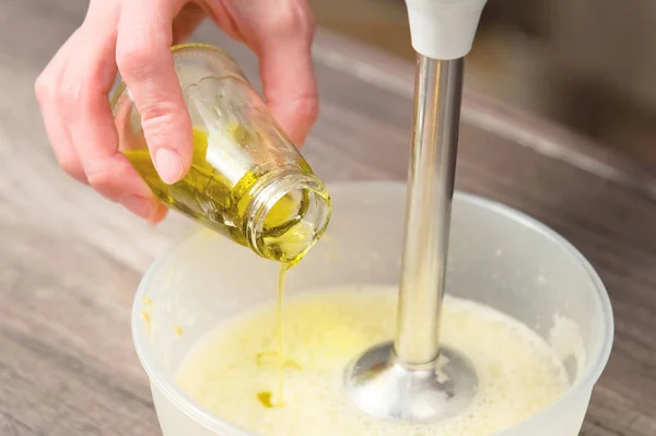 Hautnah die Mischung aus hausgemachter Mayonnaise mit einem Mixer in einer Plastikschüssel aufschlagen. Olivenöl — Stockfoto