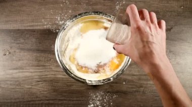 Ev yapımı kek veya bisküvi pişirme yakın çekim. Kimyasallar olmadan lezzetli ve sağlıklı pişirme. Kadın eller un ve yumurta ile kase bir bardak şeker ekleyin. Yukarıdan görünüm