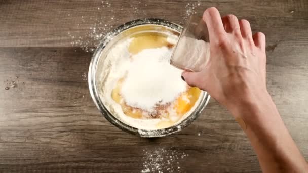 自家製ケーキやビスケット料理のクローズアップ。化学薬品なしでおいしいと健康的なベーキング。女性の手は、小麦粉と卵でボウルにガラスから砂糖を追加します。上からの眺め — ストック動画
