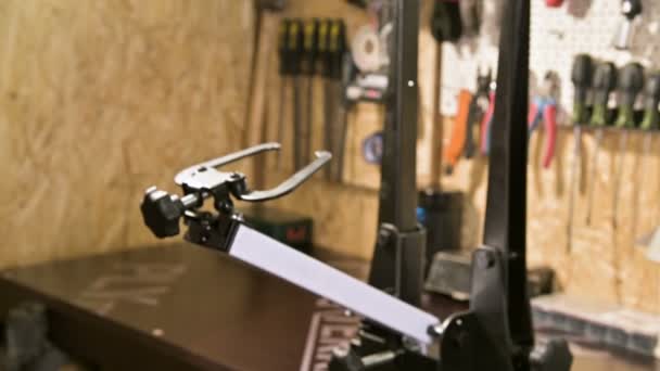 Young male bicycle repairman with a specialized wrench on a stand in the workshop, tightening the spokes of the wheel, eliminating the beating of the rim — Stock Video