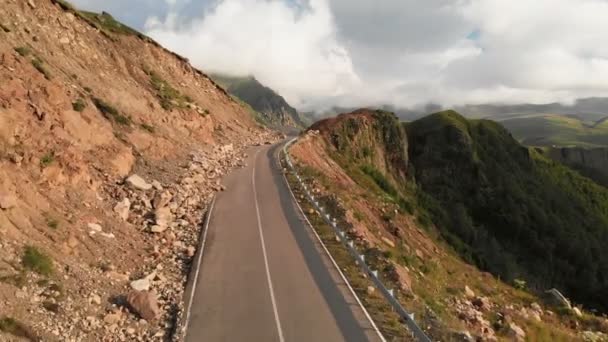 Vista aérea vuelo bajo primer plano en un paisaje con un camino de montaña asfalto serpentina en un profundo desfiladero. El concepto de comunicaciones de transporte en zonas montañosas remotas — Vídeo de stock