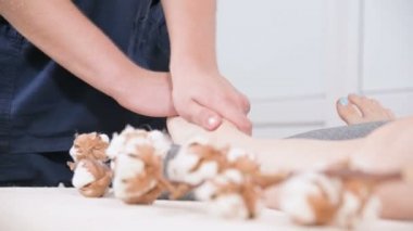 Yakın çekim bir erkek fizyoterapist bir güzellik ve sağlık spa genç bir kıza ayak masajı yapıyor. Ayak ve vücut bakım konsepti