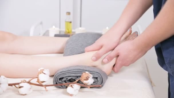 Close-up of a male physiotherapist doing foot massage to a young girl in a beauty and health spa. Foot and body care concept — Stock Video