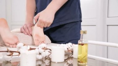 Yakın çekim bir erkek fizyoterapist bir güzellik ve sağlık spa genç bir kadına ayak ve topuklu ayak masajı yapıyor. Ayak ve vücut bakım konsepti