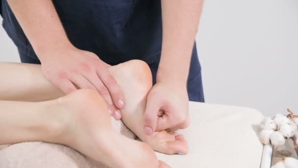 Gros plan d'un physiothérapeute masculin faisant un massage des pieds et des talons à une jeune femme dans un spa de beauté et de santé. Concept de soins des pieds et du corps — Video