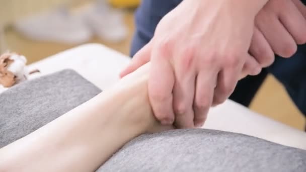 Close-up de um fisioterapeuta do sexo masculino fazendo massagem nos pés para uma jovem em um spa de beleza e saúde. Conceito de cuidados com os pés e o corpo — Vídeo de Stock