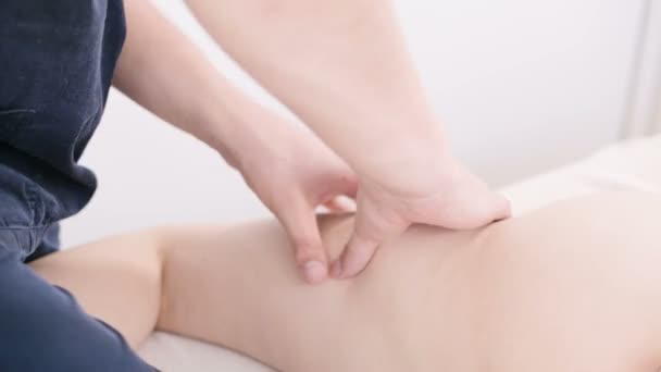 Primer plano de un fisioterapeuta masculino haciendo un ligero masaje para calentar las caderas y las nalgas de una joven en un salón de spa profesional junto a una ramita de algodón. concepto de cuidado corporal de masaje 4K — Vídeo de stock