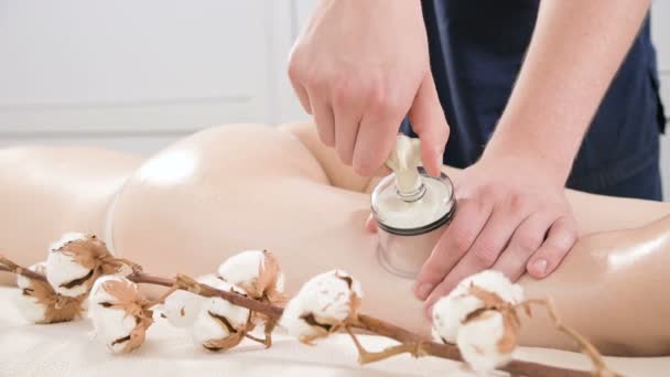 Nahaufnahme eines männlichen Physiotherapeuten stellt ein Vakuumgefäß auf, um einer jungen Frau eine Anti-Cellulite-Massage des Gesäßes und der Oberschenkel zu geben. das Konzept der Pflege der Gesundheit des weiblichen Körpers — Stockvideo