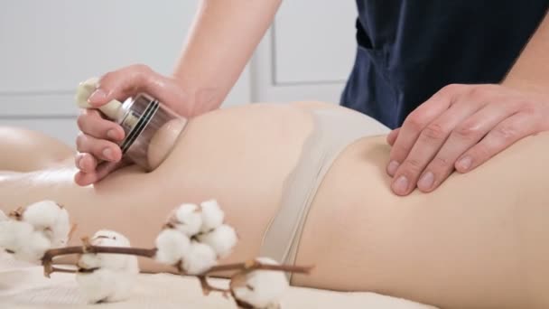 Primer plano de un fisioterapeuta masculino haciendo un anti-celulitis puede masaje de las nalgas y las caderas de una mujer joven. El concepto de cuidado y mantenimiento de la salud del cuerpo y la piel de la mujer — Vídeo de stock