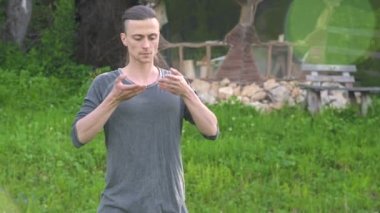 Ortalama bir plan Hint giysi ve pantolon Aladdin uygulamaları qigong bir genç adam eski bir kulübe yanında yaz aylarında qi enerji açık havada çalışırken egzersizleri yaparken