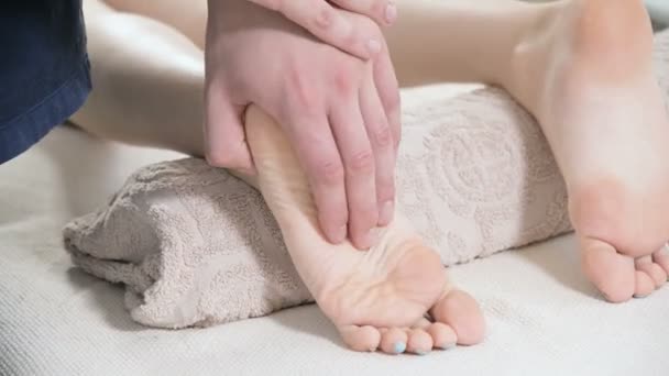 Close-up de um fisioterapeuta do sexo masculino fazendo pé e saltos massagem nos pés para uma jovem mulher em um spa de beleza e saúde. Conceito de cuidados com os pés e o corpo — Vídeo de Stock