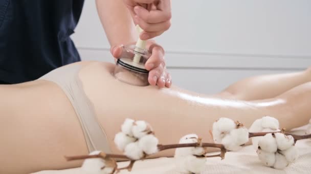 Yakın çekim bir erkek fizyoterapist genç bir kadın bir anti-selülit kalça ve uyluk masaj vermek için bir vakum kavanoz kurar. Kadın vücudunun sağlık bakım kavramı — Stok video