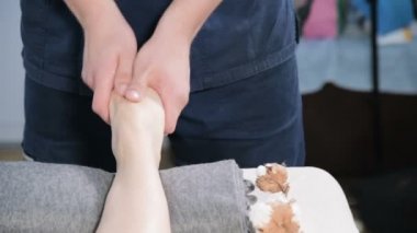 Yakın çekim bir erkek fizyoterapist bir güzellik ve sağlık spa genç bir kıza ayak masajı yapıyor. Ayak ve vücut bakım konsepti