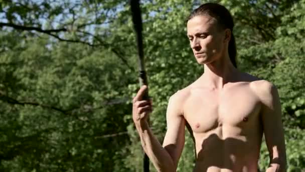 Medium close-up Morning training of a long-haired man for a fire show. Preparation for a performance without fire with torches and chains on a sunny summer morning in the outdoor — Stock Video