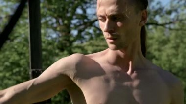 Yangın gösterisi için uzun saçlı bir adamın yakın çekim sabah eğitimi. Yeşil bir ormanın yanında açık havada güneşli bir yaz sabahı meşaleler ve zincirler ile ateş olmadan bir performans için hazırlık.