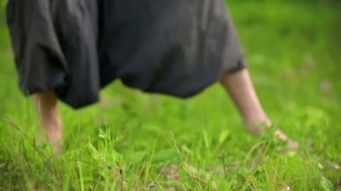 Çimenlerde pratik yapan bir adamın bacaklarının yakın çekim. Qigong egzersizleri çıplak ayak geçiş. Oryantal kültür 4k bir spor yaşam tarzı kavramı