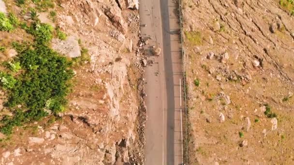 深い峡谷に山のアスファルト道路蛇と風景の上に低空飛行の低い飛行クローズアップ。遠隔地における交通通信の概念 — ストック動画