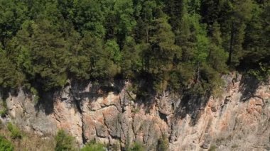 Yüksek kayalıklar ve yoğun bir orman ile derin bir kayalık geçit üzerinde kamera nın uçuş havadan görünümü. Güneşli bir yaz gününde yaban hayatı
