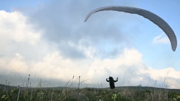 Un atleta parapente macho levanta un ala en un outdor contra el telón de fondo de las nubes de la tarde, pero no puede volar. Fracaso al tratar de despegar — Vídeo de stock