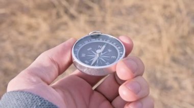 Yakın-up erkek el bir outdor sarı kuru çim bir arka plan üzerinde manyetik bir pusula tutar. Açık alanlarda ve dağlarda güvenilir navigasyon kavramı