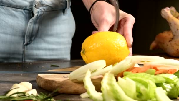 Zblízka ženské ručičky dělají díry v citrónu, aby se mačkají na řezací desce vedle sekaných listů a okurek. Zdravé a zdravé vegetariánské potraviny — Stock video