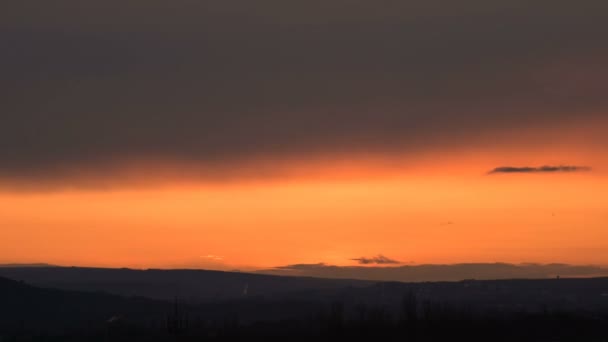 Тімелапс заходу сонця за хмарами на заході сонця над маленьким містом. Закручені хмари перед заходом сонця. Низький ключ — стокове відео