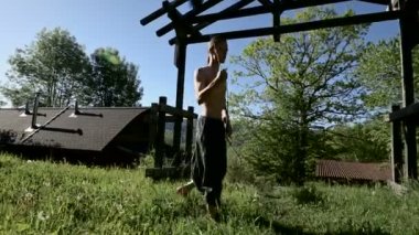 Uzun menzilli bir adamın yangın gösterisi için uzun çekim sabah eğitimi. Yeşil bir ormanın yanında açık havada güneşli bir yaz sabahı meşaleler ve zincirler ile ateş olmadan bir performans için hazırlık.