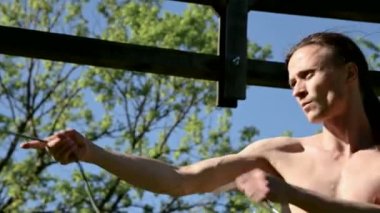 Bir yangın gösterisi için uzun saçlı bir adamın orta yakın çekim sabah eğitimi. Açık havada güneşli bir yaz sabahı meşaleler ve zincirler ile ateş olmadan bir performans için hazırlık