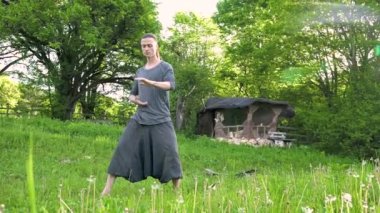 Genel plan Hint giysi ve pantolon Aladdin uygulamaları qigong genç bir adam eski bir kulübe 4k yanında yaz açık havada qi enerji ile çalışan egzersizleri yaparken