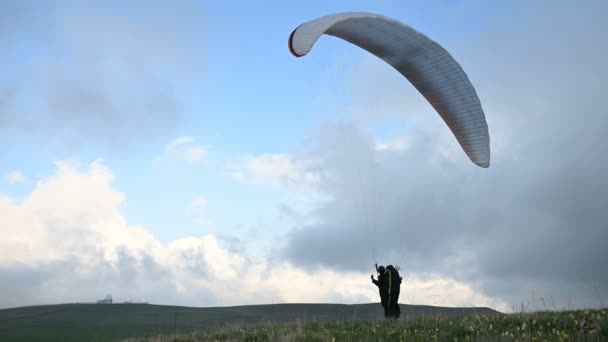 Un atleta parapente macho levanta un ala en un outdor contra el telón de fondo de las nubes de la tarde, pero no puede volar. Fracaso al tratar de despegar — Vídeos de Stock