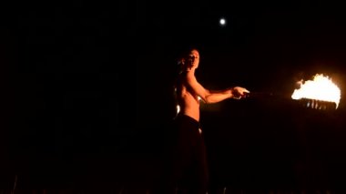 Ateş gösterisi. Adam yanan iki meşaleyle hokkabazlık yapıyor. Gece şovu. Fakirin ustalığı. Düşük açı
