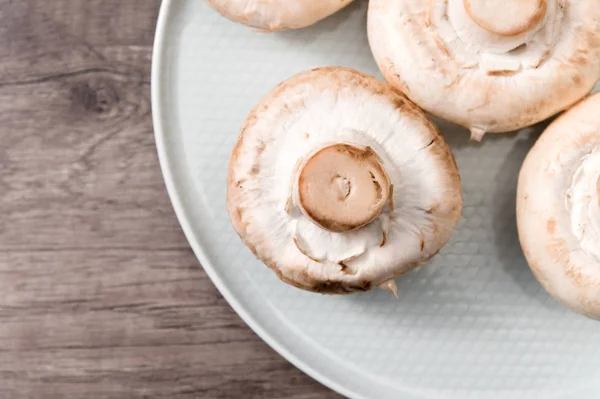 Primer plano de hongos blancos en un plato blanco sobre una mesa de madera oscura. Comida vegetariana saludable — Foto de Stock