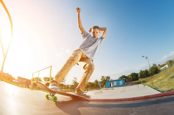 Ein Teenager in kurzen Hosen und Mütze macht im sommerlichen Sonnenuntergang einen Allie-Stunt auf einer Rampe in einem Skatepark in einem Wohngebiet. das Konzept der Skatkultur und der Jugendfreizeit — Stockfoto