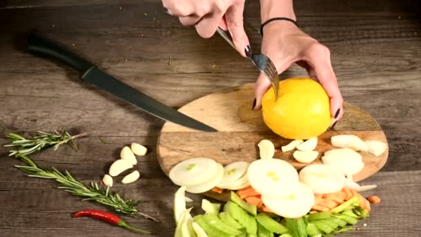 Close-up van vrouwelijke handen het maken van gaten in een citroen voor knijpen op een snijplank naast gehakte muntblaadjes en komkommers. Gezond en gezond vegetarisch eten — Stockvideo