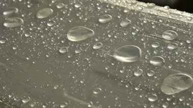 Yüzeyde farklı boyutlarda yağmur damlalarının yakın çekim film sarın kaplı. Nem havası ve nem konsepti