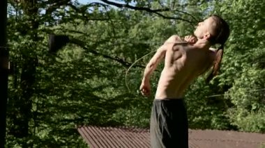 Bir yangın gösterisi için uzun saçlı bir adamın Sabah eğitim vurdu. Yeşil bir ormanın yanında açık havada güneşli bir yaz sabahı meşaleler ve zincirler ile ateş olmadan bir performans için hazırlık.