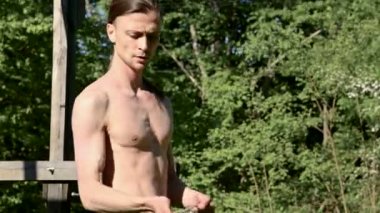 Bir yangın gösterisi için uzun saçlı bir adamın orta yakın çekim sabah eğitimi. Açık havada güneşli bir yaz sabahı meşaleler ve zincirler ile ateş olmadan bir performans için hazırlık