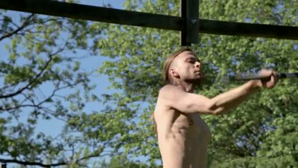 Tiro médio Treinamento matinal de um homem de cabelos compridos para um show de fogo. Preparação para uma performance sem fogo com tochas e correntes em uma manhã ensolarada de verão ao ar livre ao lado de uma floresta verde . — Vídeo de Stock