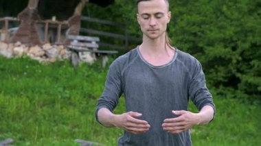 Ortalama bir plan Hint giysi ve pantolon Aladdin uygulamaları qigong bir genç adam eski bir kulübe yanında yaz aylarında qi enerji açık havada çalışırken egzersizleri yaparken