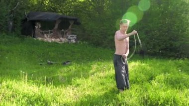 Uzun atış Uzun saçlı ve çıplak gövdeli genç bir adam dövüş sanatı konusunda eğitilir ve bir yaz sabahı açık havada rotasyonda bir personel veya yük halat ile konuşmadan önce. Düşük açı
