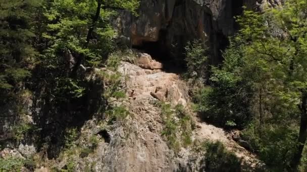 A man in a hat sits on the edge of a cliff in the lotus position and meditates contemplating infinity. Aerial view 4k — Stock Video