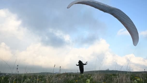 Un atleta parapente macho levanta un ala en un outdor contra el telón de fondo de las nubes de la tarde, pero no puede volar. Fracaso al tratar de despegar — Vídeos de Stock
