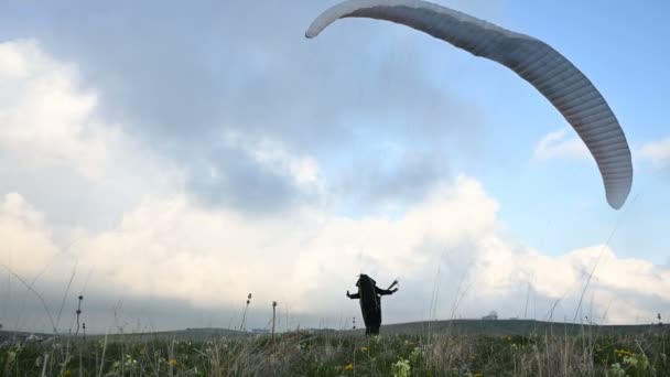 Um atleta do sexo masculino parapente levanta uma asa em um outdor contra o pano de fundo das nuvens da noite, mas não pode voar. Falha ao tentar decolar — Vídeo de Stock