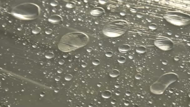 Primer plano de gotas de lluvia de diferentes tamaños en la superficie cubierta con película adhesiva. Concepto de humedad y clima húmedo — Vídeo de stock