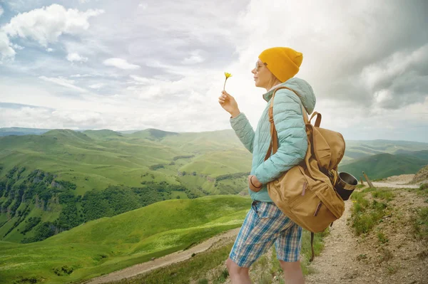 Portrait of a girl in a hat and sunglasses is holding a flower in early spring on nature. The concept of unity with nature — Stock Photo, Image