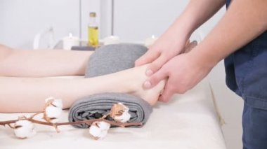 Yakın çekim bir erkek fizyoterapist bir güzellik ve sağlık spa genç bir kıza ayak masajı yapıyor. Ayak ve vücut bakım konsepti